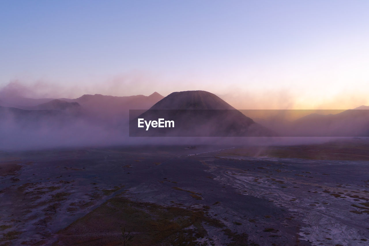 Scenic view of volcano against clear sky during sunset