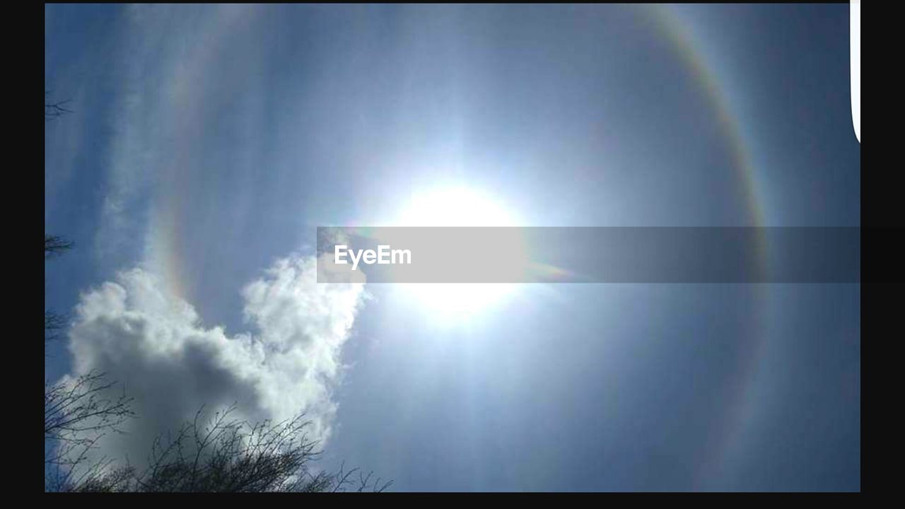 LOW ANGLE VIEW OF SUN SHINING THROUGH CLOUDS