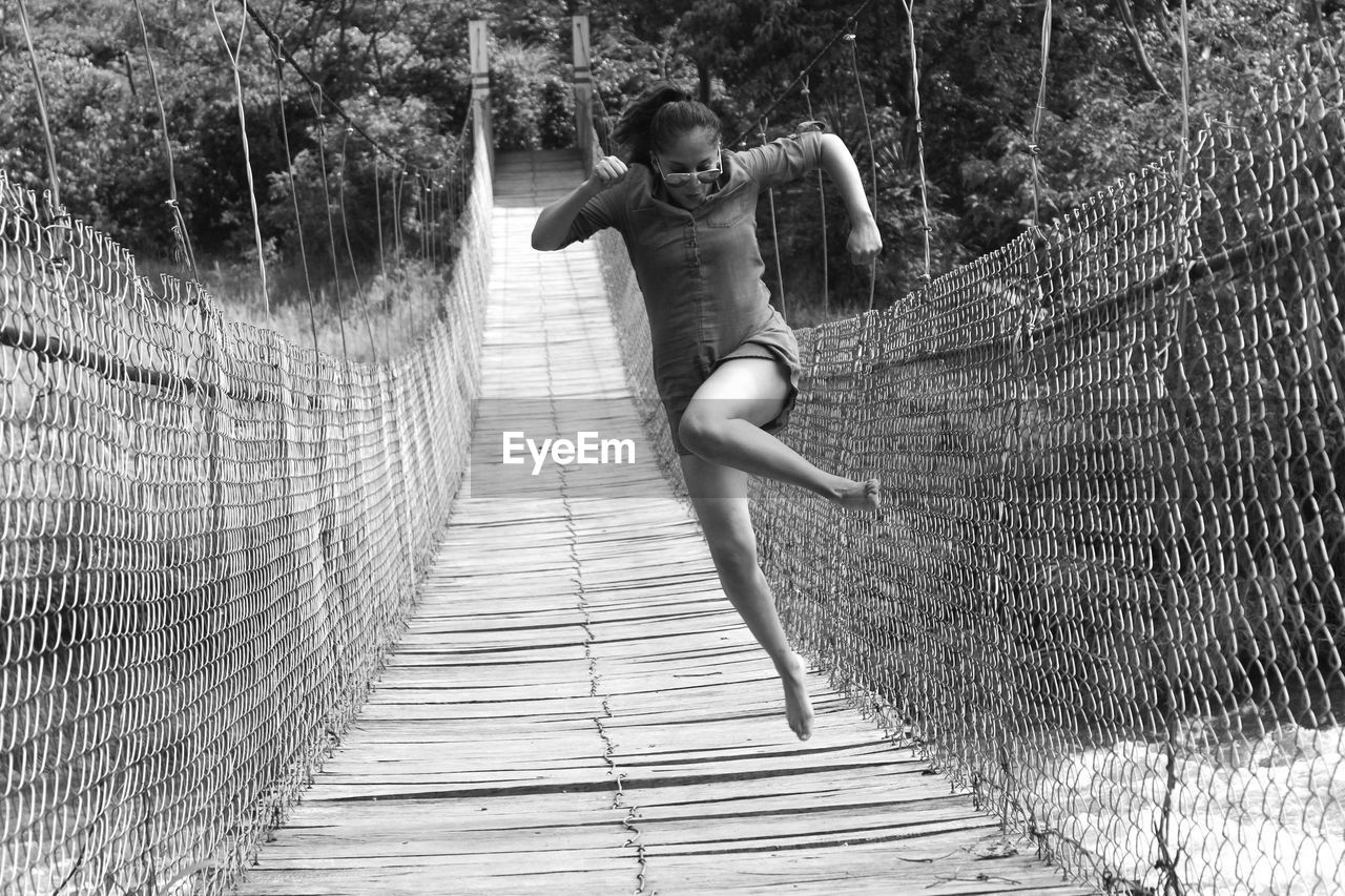 FULL LENGTH OF BOY ON FOOTBRIDGE AGAINST PLANTS