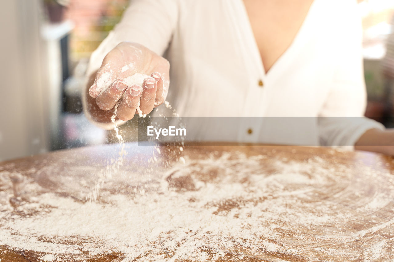 MIDSECTION OF WOMAN PREPARING FOOD AT KITCHEN