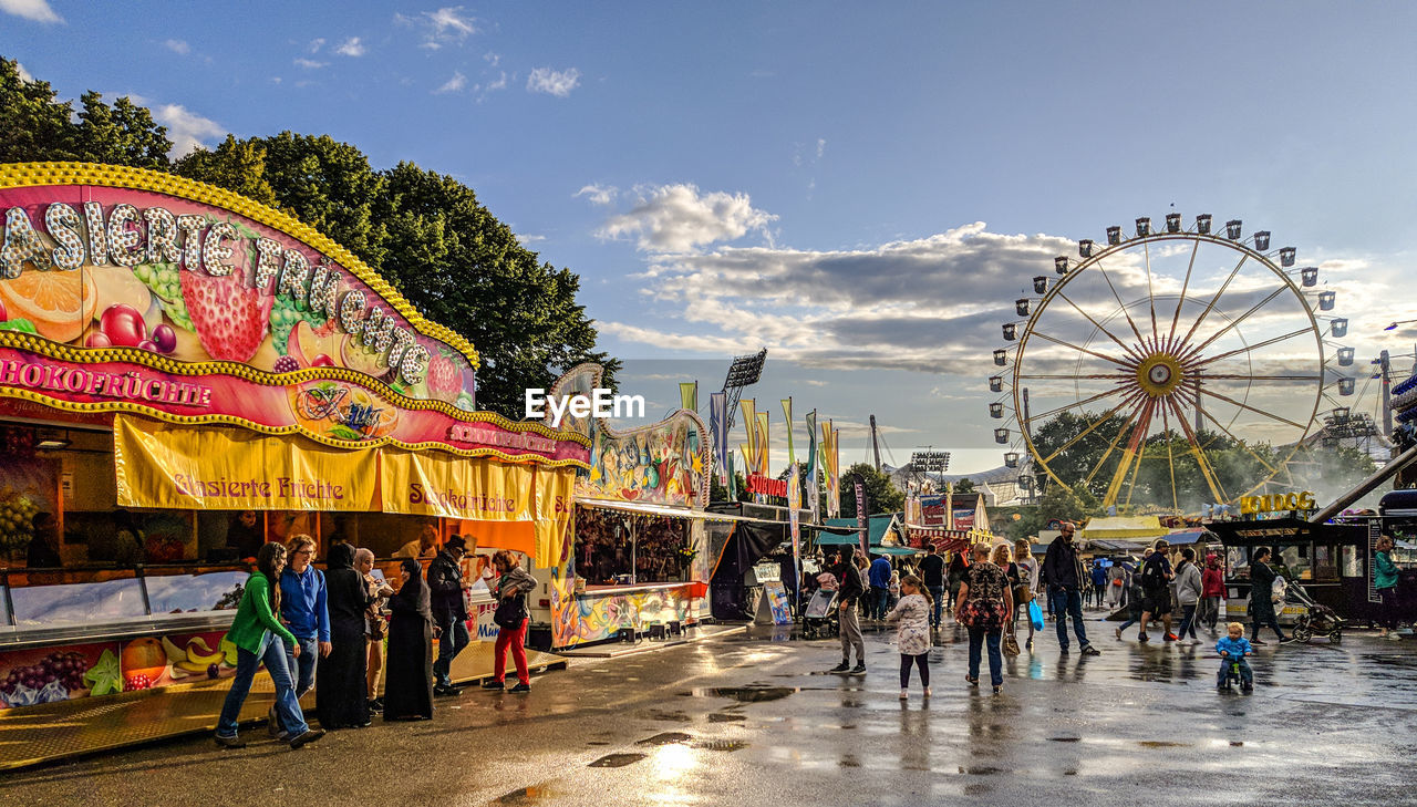 GROUP OF PEOPLE AT AMUSEMENT PARK AGAINST SKY