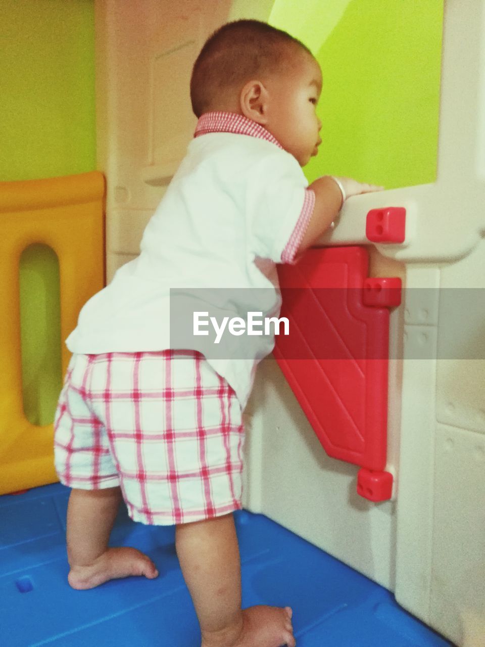 Full length of cute baby boy standing on toy