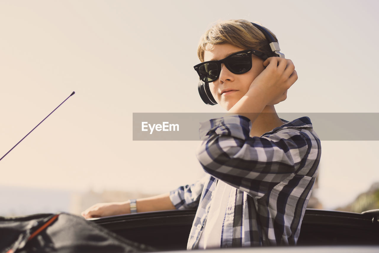 Young boy enjoy music standing on the open roof of a convertible car. teenager listening music
