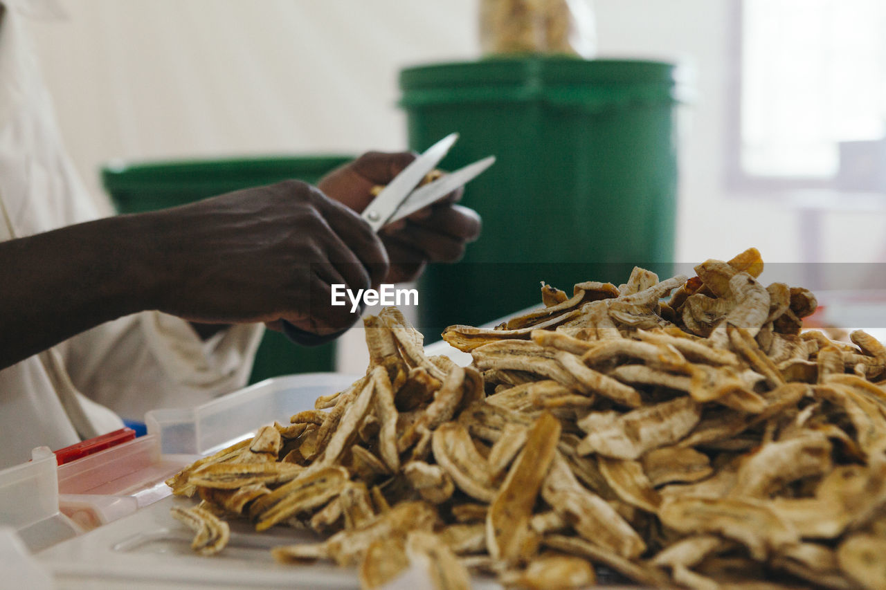 Midsection of man cutting dried bananas