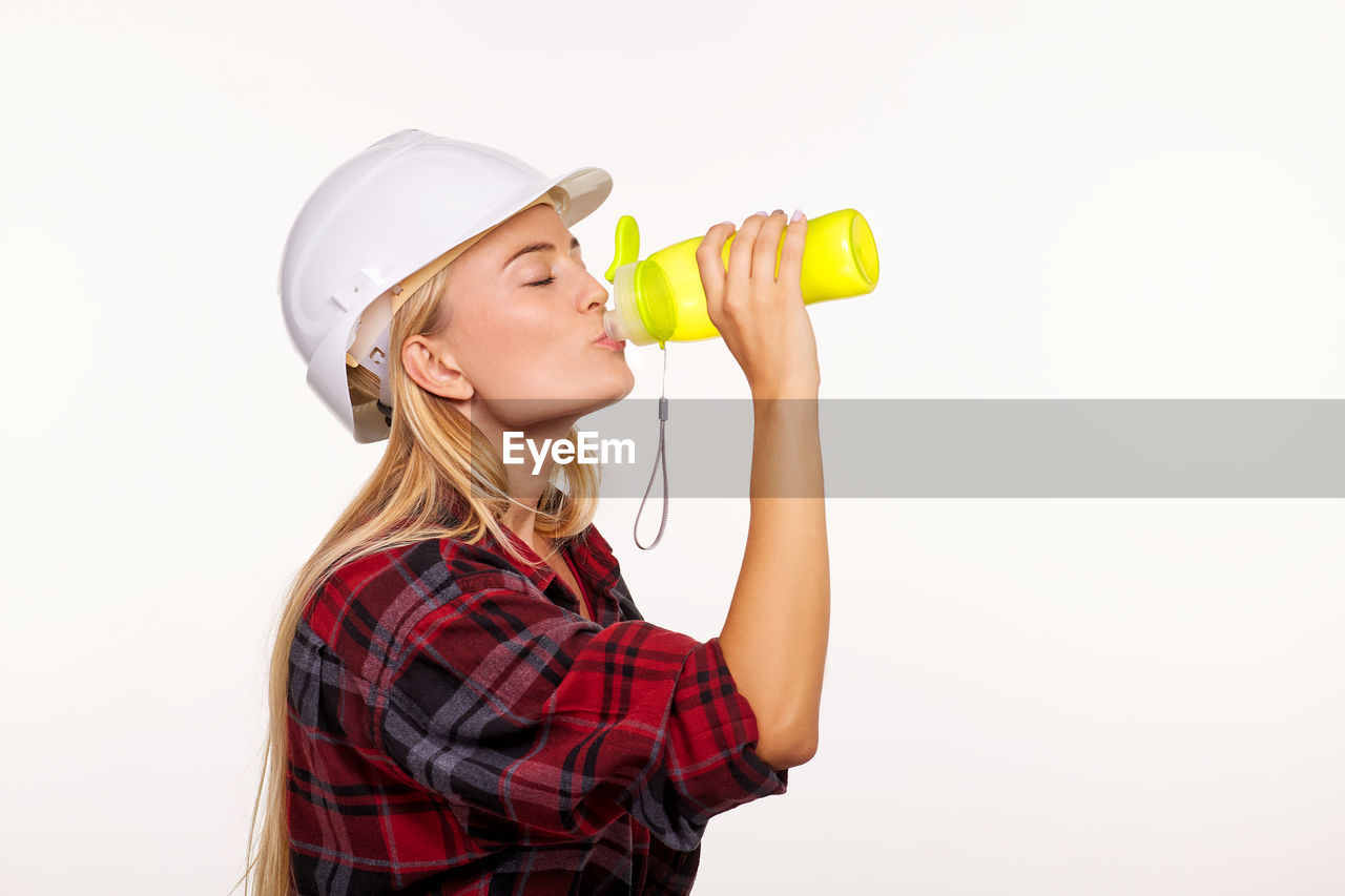 Close-up of woman drinking water against white background