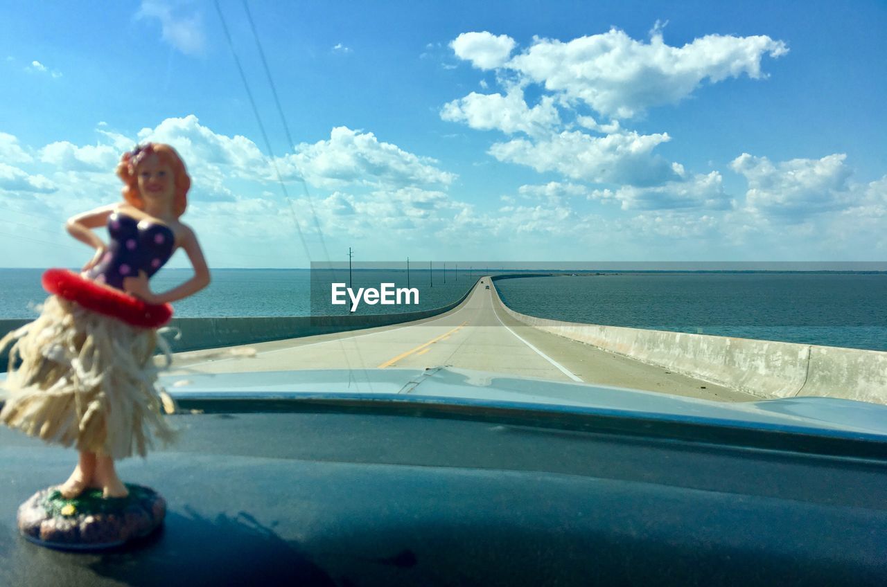 REAR VIEW OF WOMAN IN CAR BY SEA