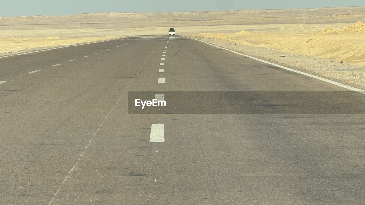 road, transportation, the way forward, road marking, asphalt, sign, marking, road surface, symbol, landscape, highway, nature, environment, land, day, vanishing point, travel, lane, tarmac, sky, diminishing perspective, scenics - nature, no people, desert, infrastructure, remote, horizon, sand, horizon over land, journey, mode of transportation, outdoors, non-urban scene, natural environment, empty road, tranquil scene, tranquility, dividing line, plain, sunlight