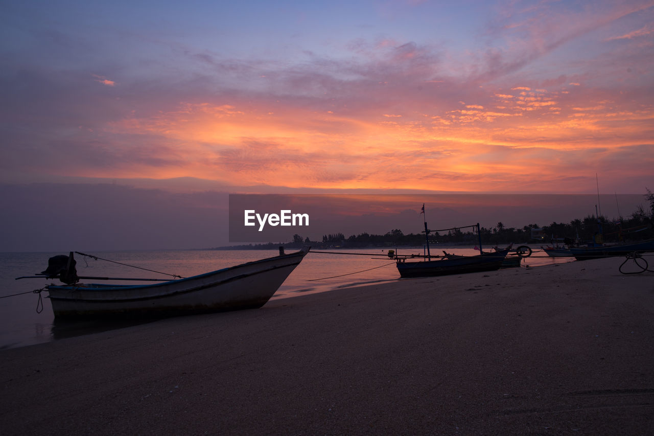 Boats moored on sea against sky during sunset