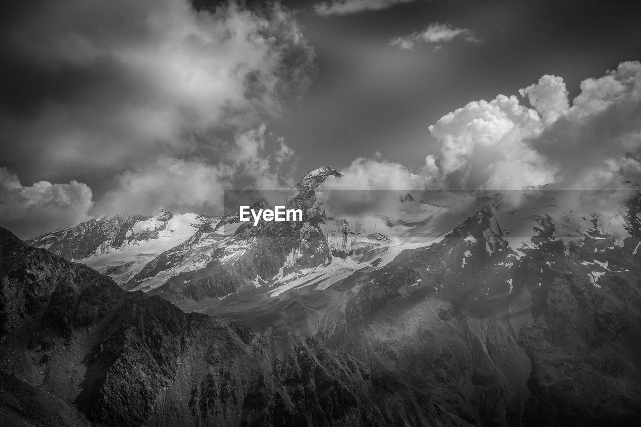 mountain, cloud, environment, sky, scenics - nature, landscape, beauty in nature, mountain range, nature, snow, darkness, land, cold temperature, winter, monochrome, mountain peak, snowcapped mountain, travel, black and white, travel destinations, no people, dramatic sky, outdoors, fog, forest, tree, plant, monochrome photography, cloudscape, tranquility, non-urban scene, pinaceae, coniferous tree, pine tree, tranquil scene, tourism, valley, high up