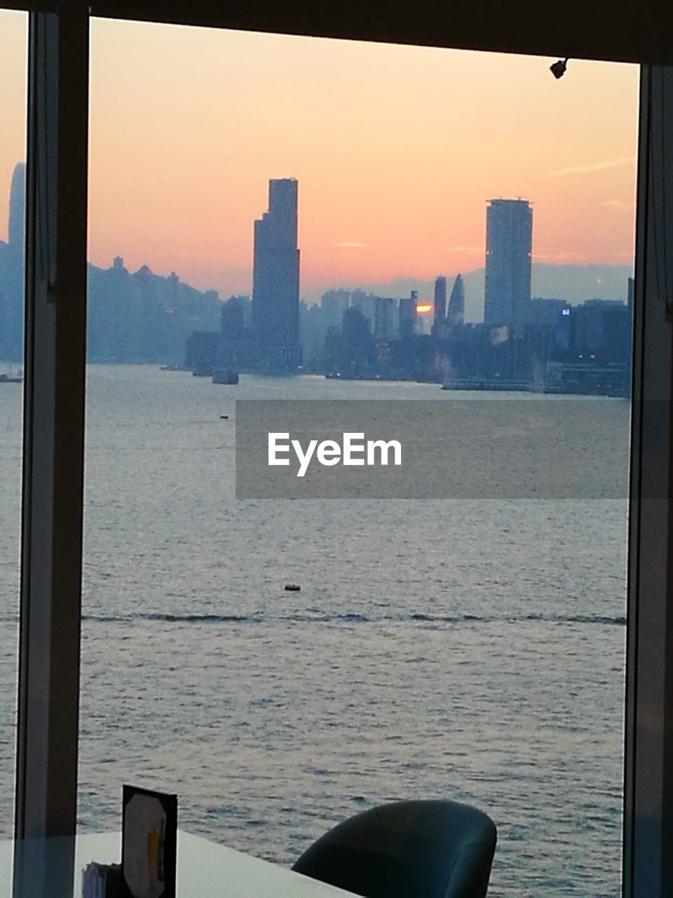 SEA BY BUILDINGS AGAINST SKY AT SUNSET