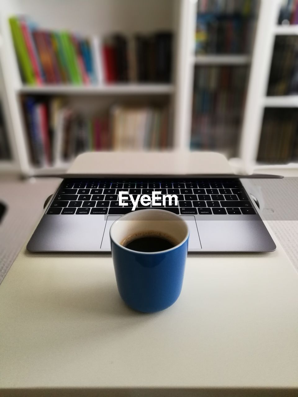 Close-up of coffee cup and laptop on table