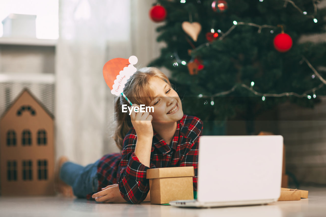 A happy little girl opens a gift under the christmas tree at home 