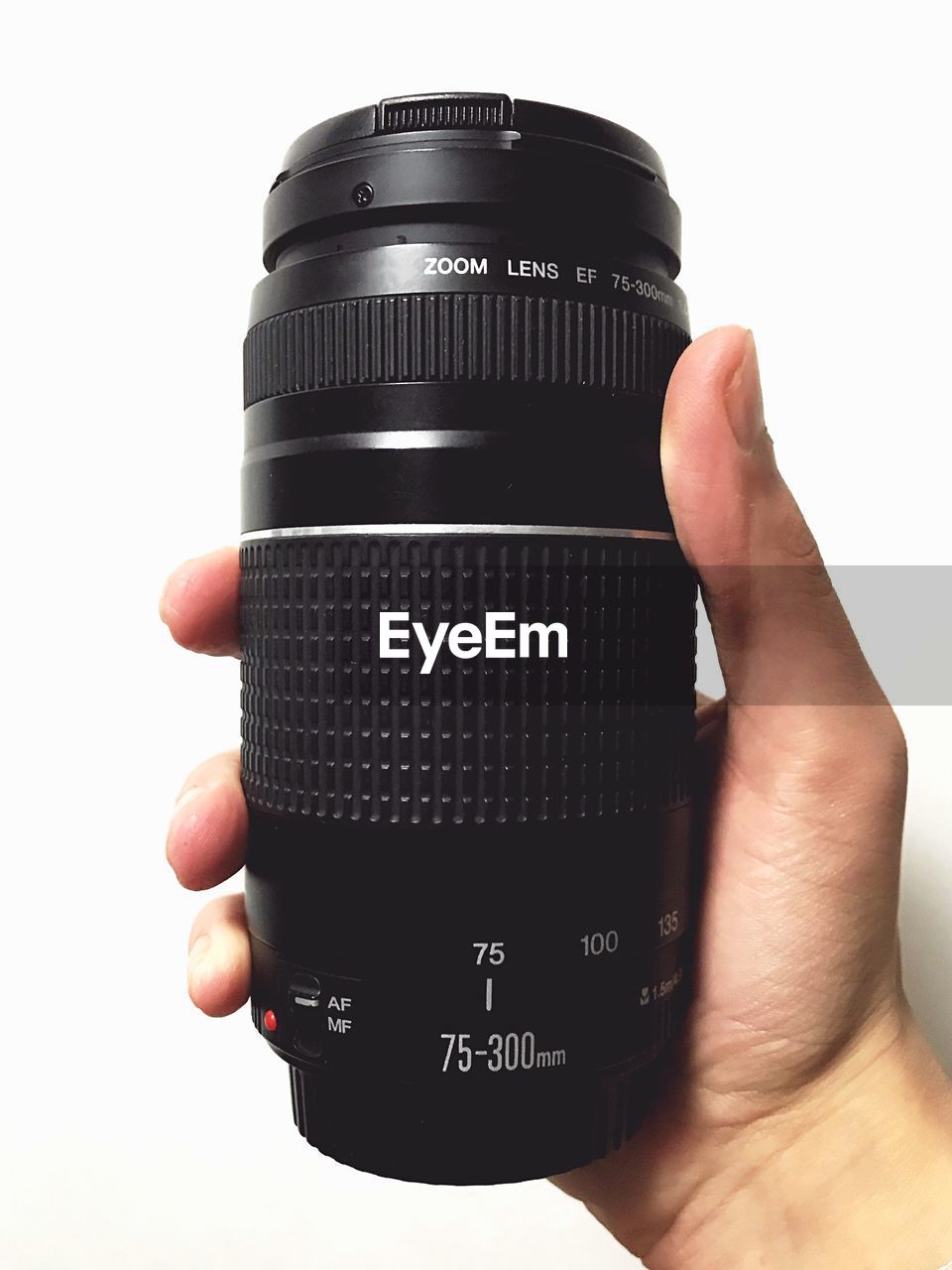 Close-up of hand holding camera lens against white background