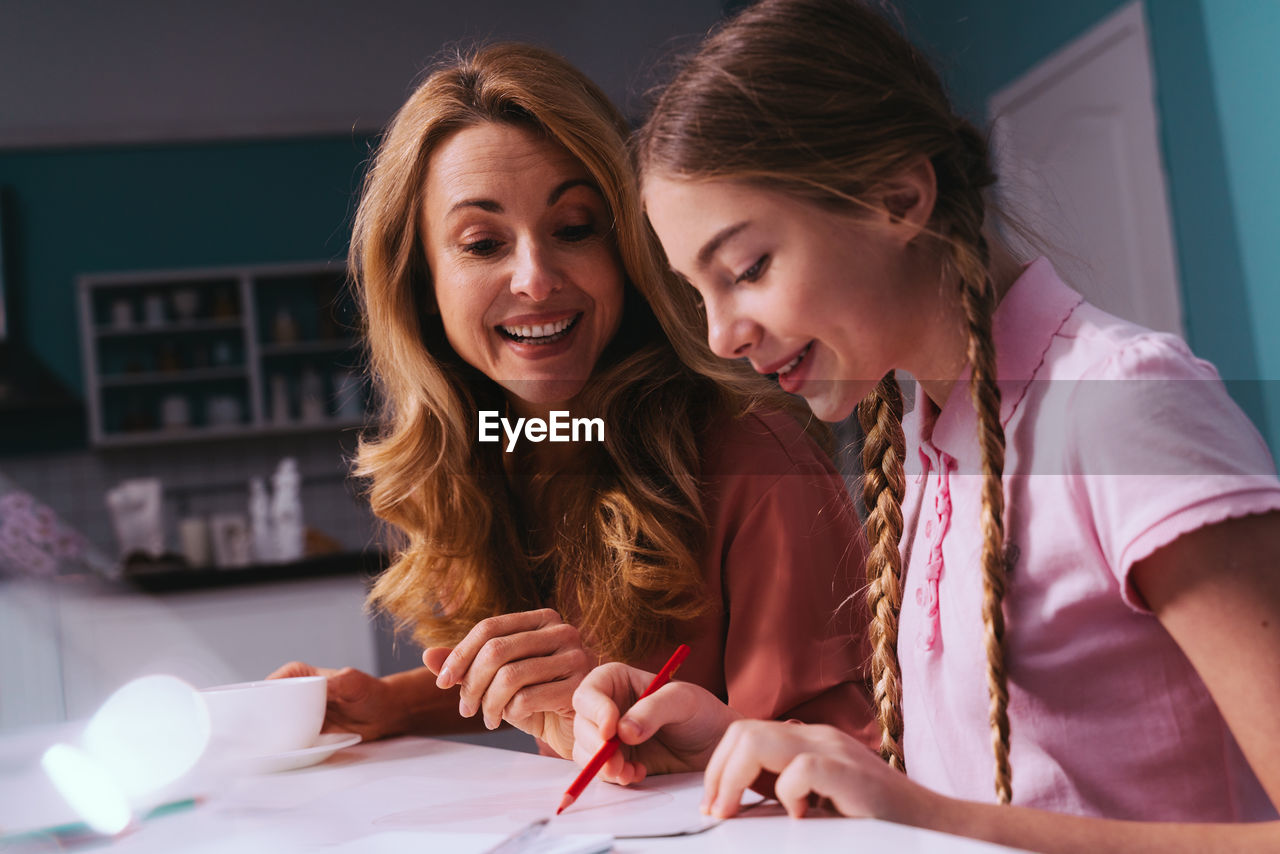 Cheerful mother and daughter discussing over studies