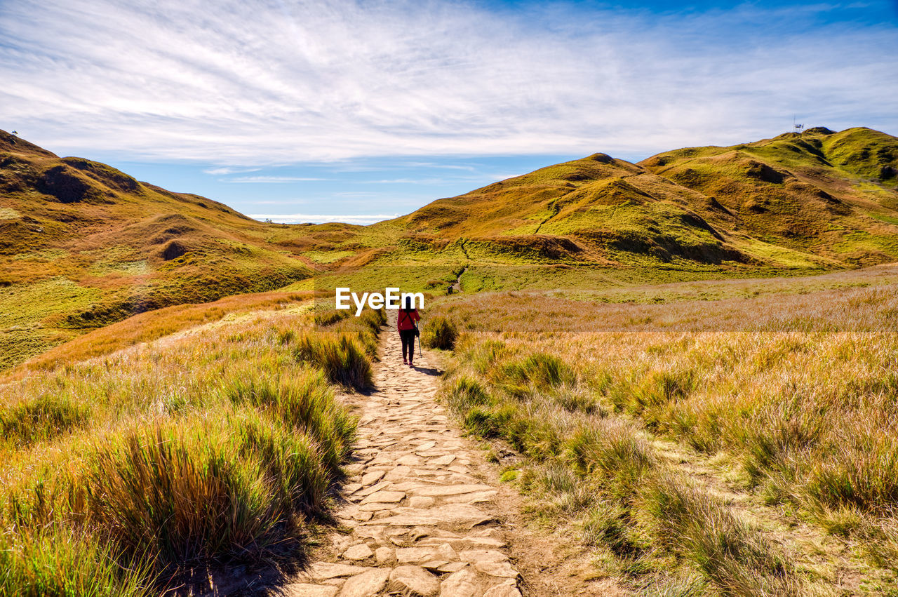 Rear view of woman walking on footpath against sky