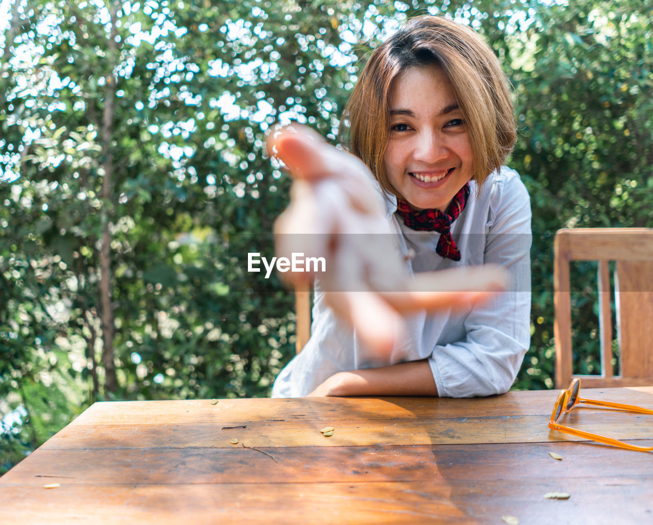 Portrait of smiling woman gesturing while sitting outdoors