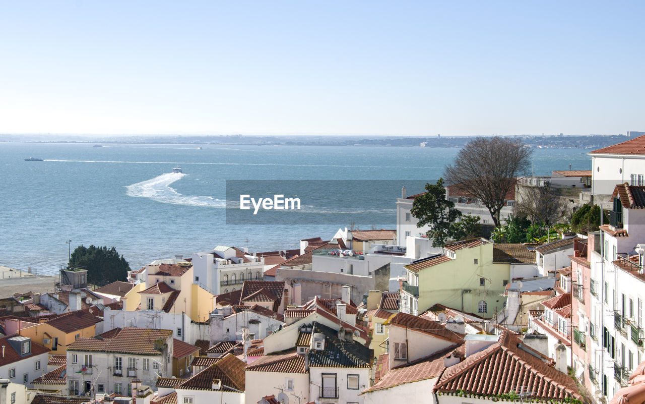 High angle view of townscape by sea against sky