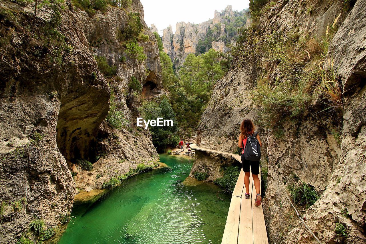 WOMAN ON ROCK BY RIVER