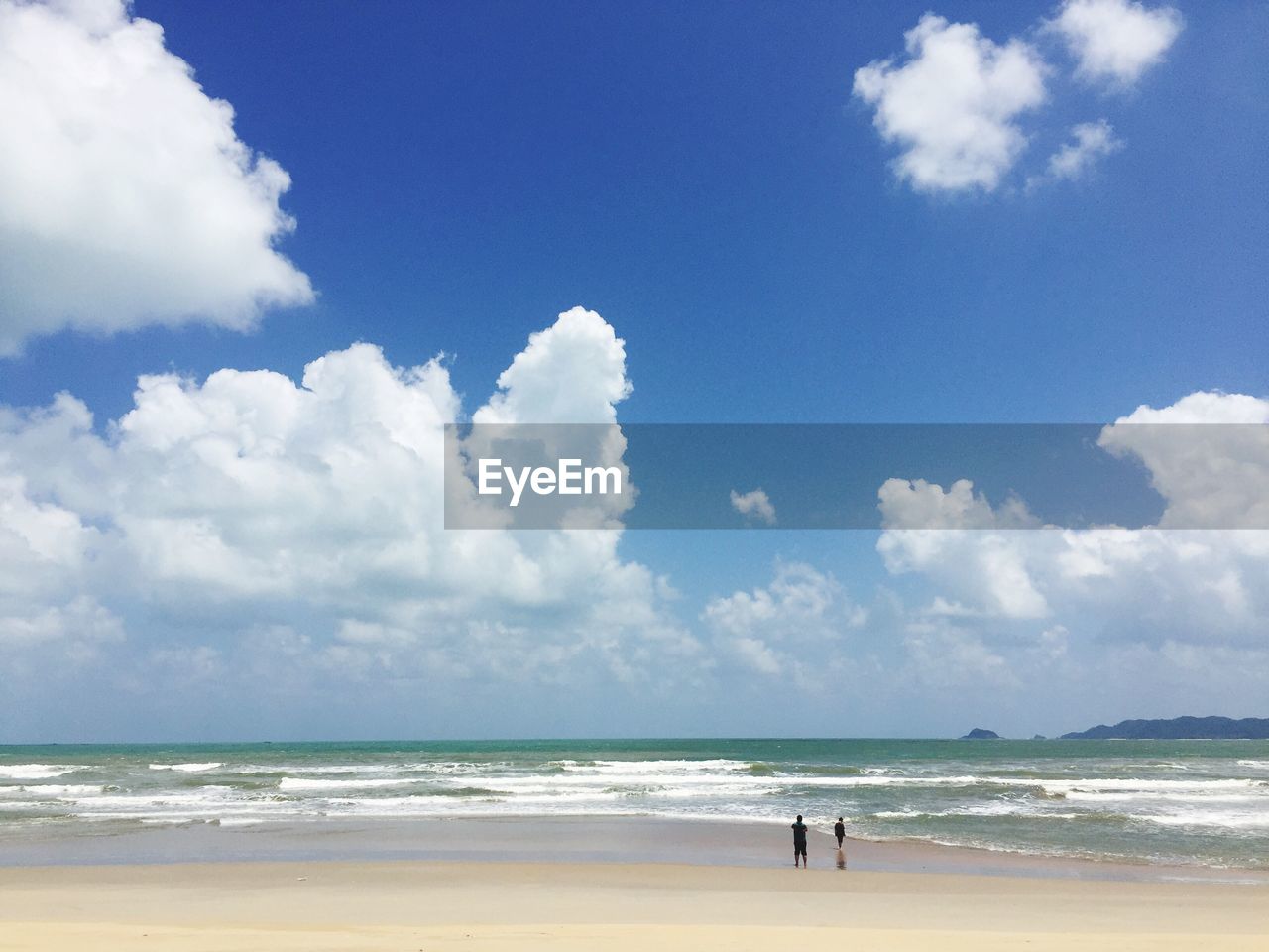 People at beach against sky during sunny day