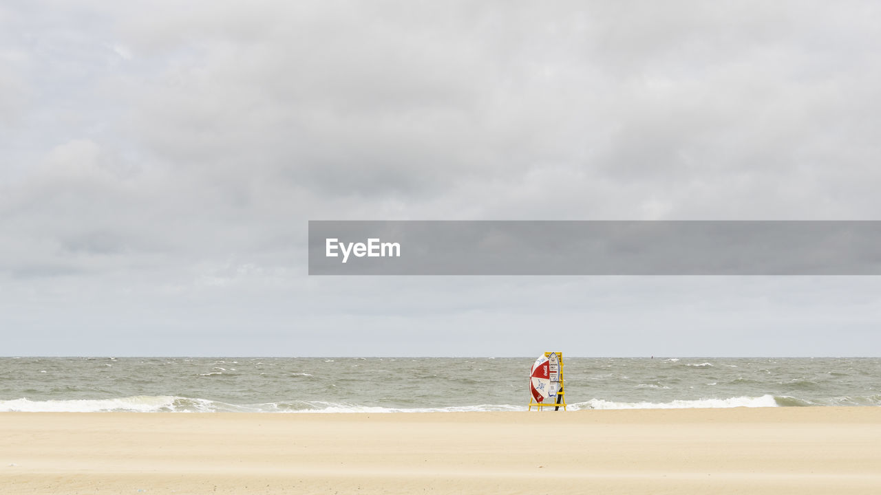 MAN WALKING ON BEACH AGAINST SEA