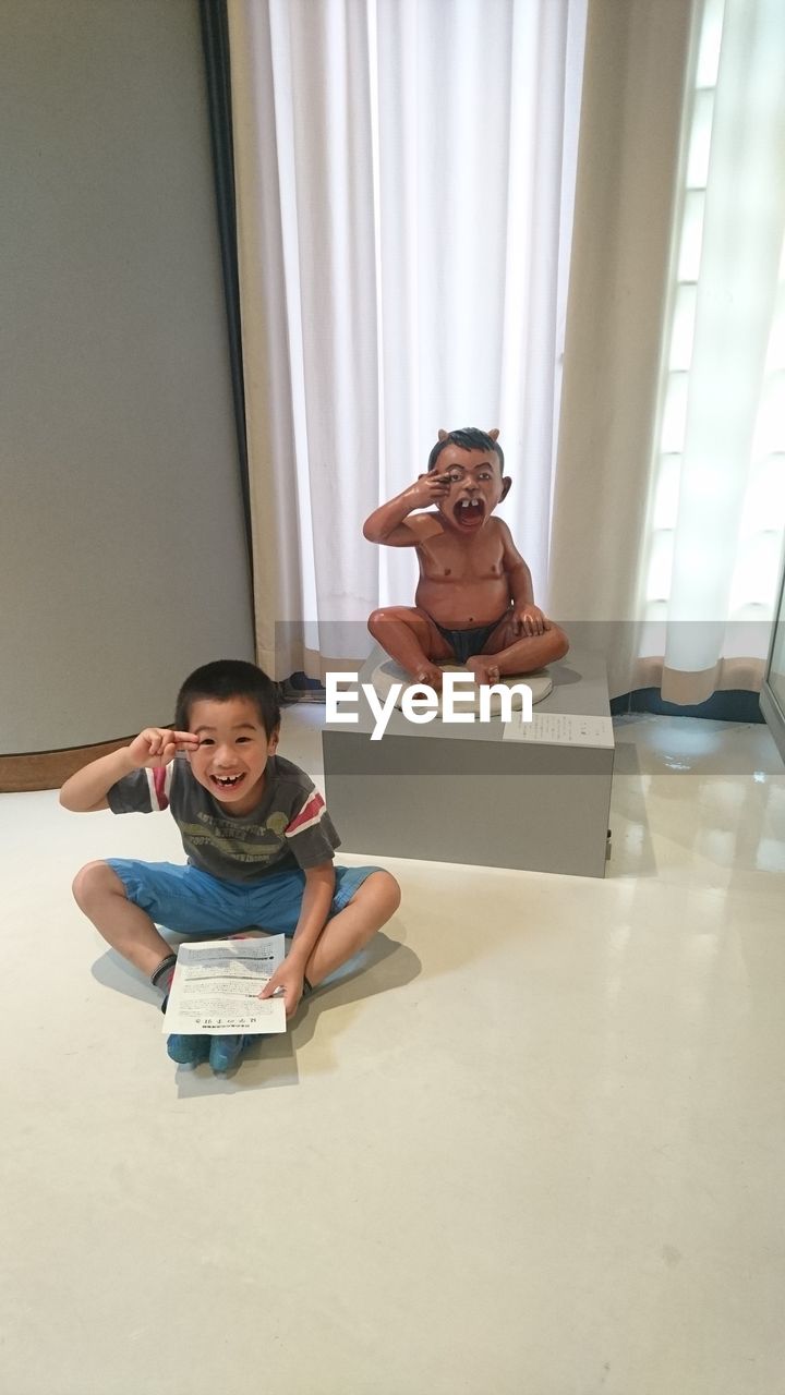 BOY SITTING ON BOOK AT HOME