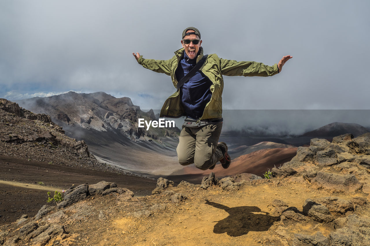 Full length of man with arms outstretched against sky