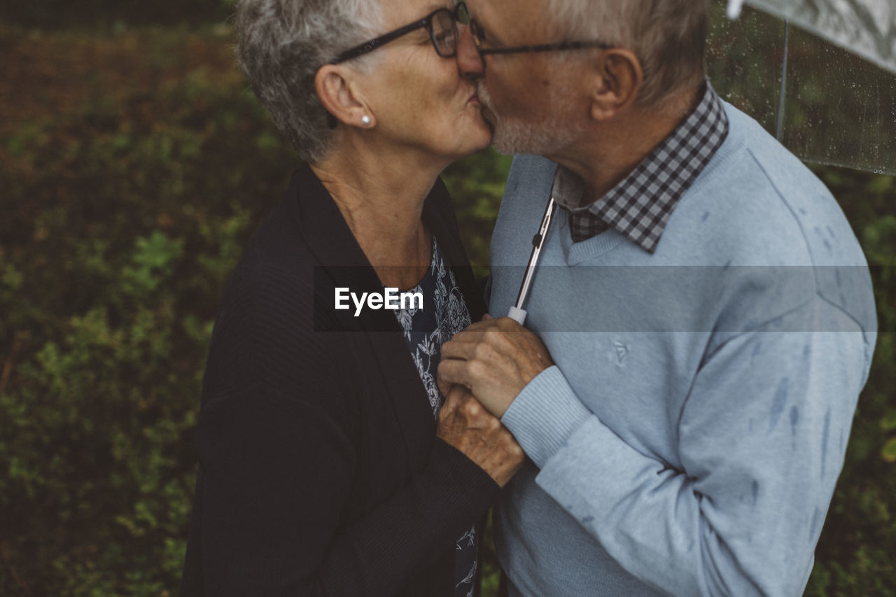 Elderly couple kissing under an umbrella