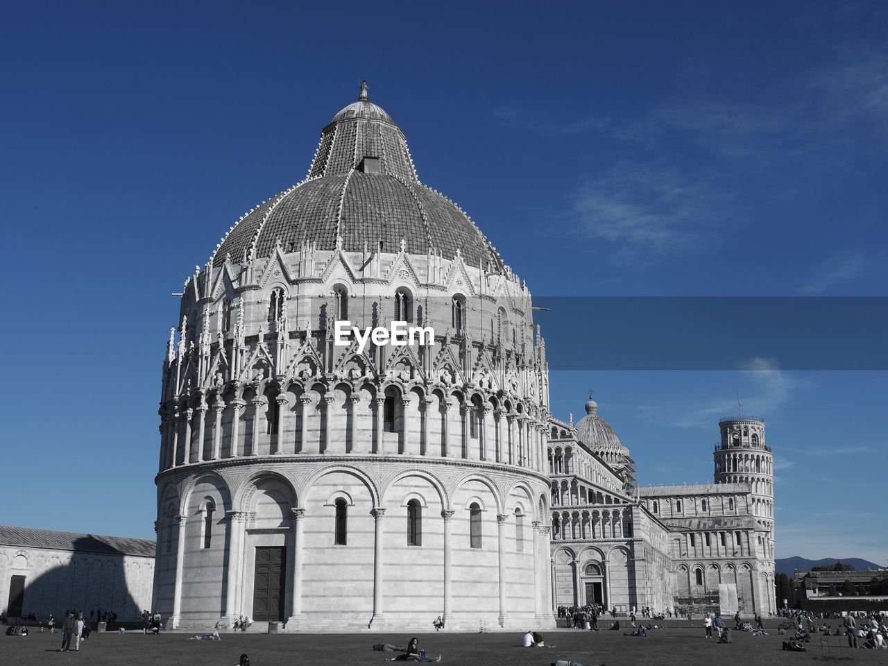 People at leaning tower of pisa against blue sky