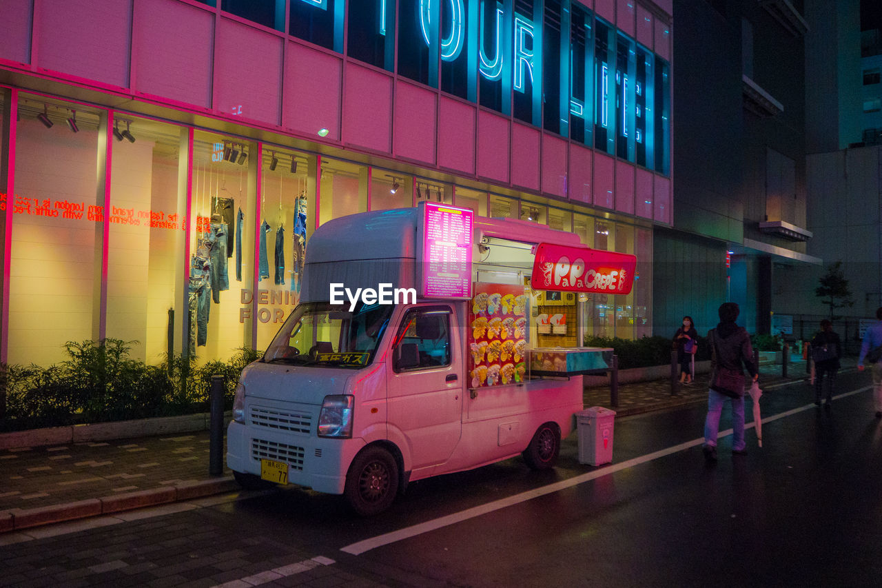 PEOPLE AT ILLUMINATED CITY STREET AT NIGHT