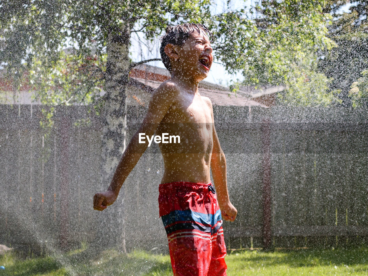 Young boy playing happily with splashing water in summer