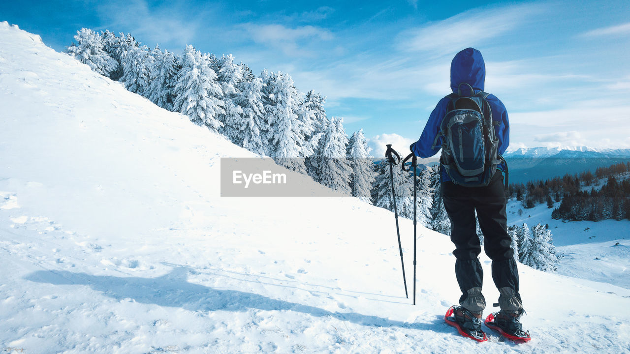 MAN STANDING ON SNOW COVERED LANDSCAPE