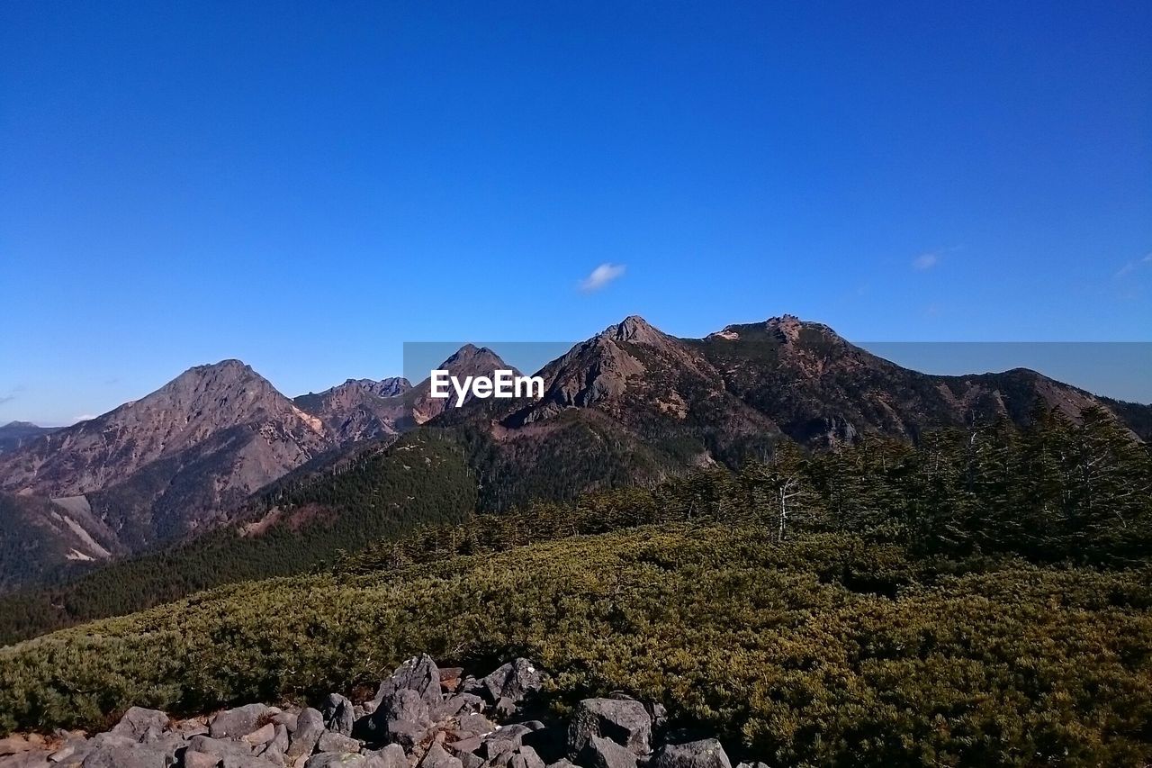 Scenic view of mountains against clear blue sky