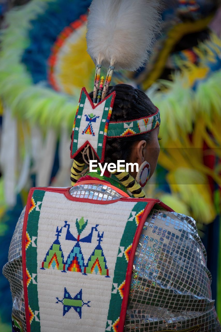 REAR VIEW OF MAN HOLDING FEATHERS