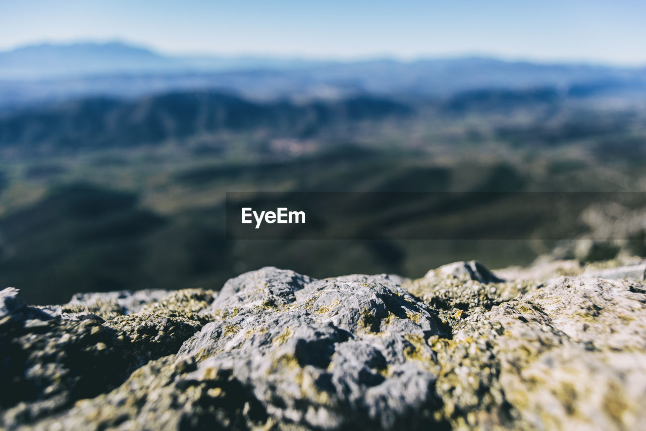 Textured stone seen up close with a defocused mountains horizon