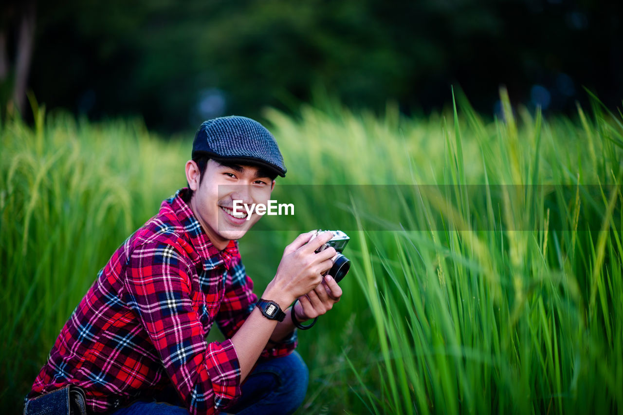 YOUNG MAN USING SMART PHONE IN FIELD