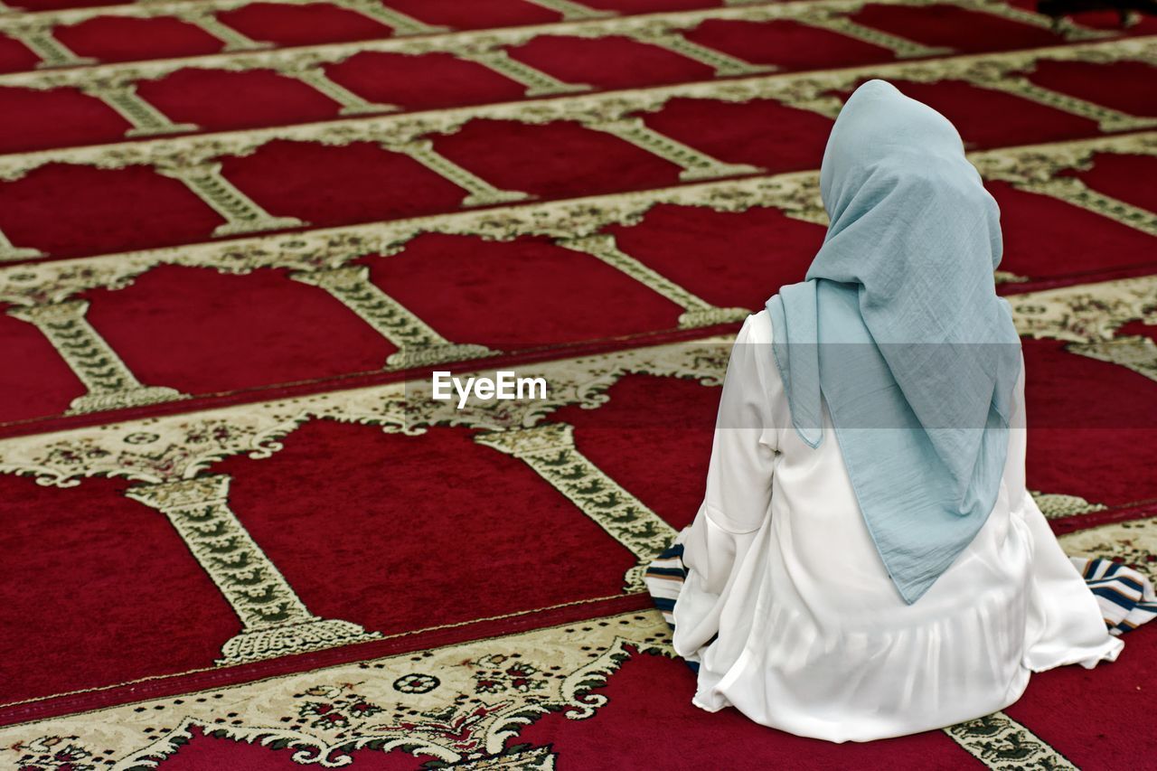 Rear view of woman sitting in mosque