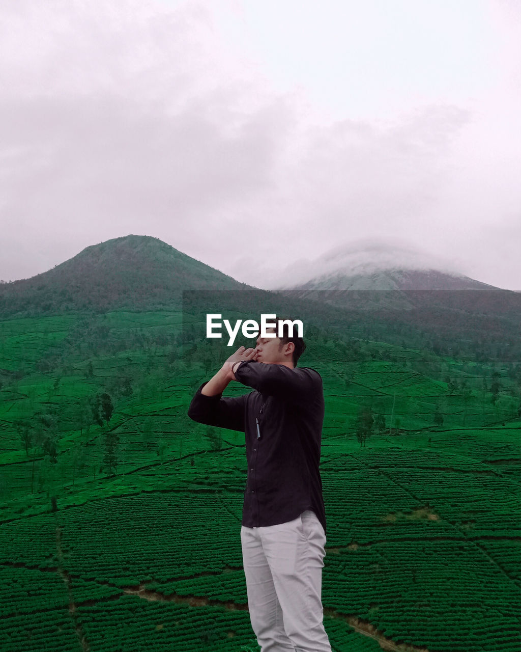 Young man standing on landscape against sky