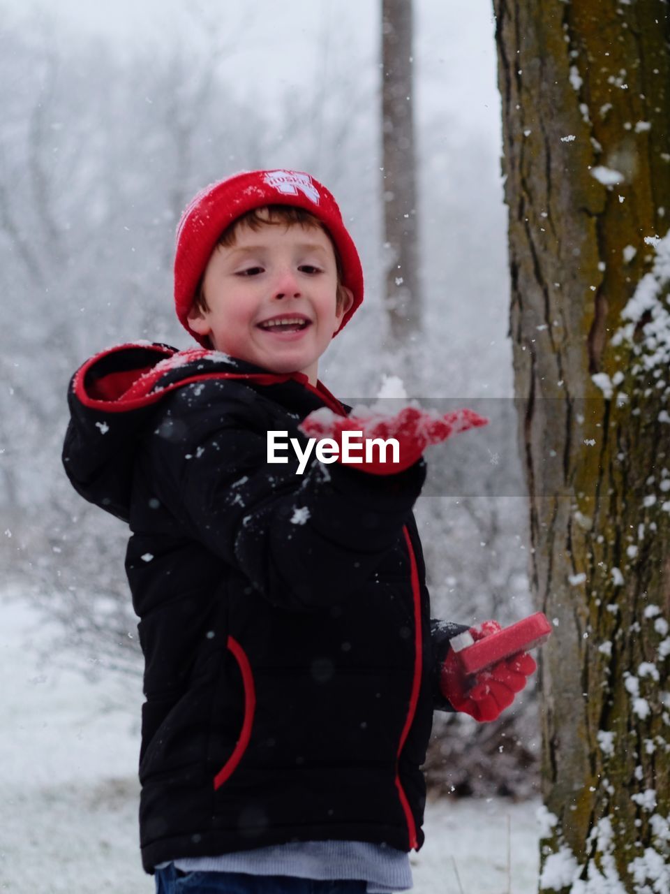 Smiling boy standing while playing in snow