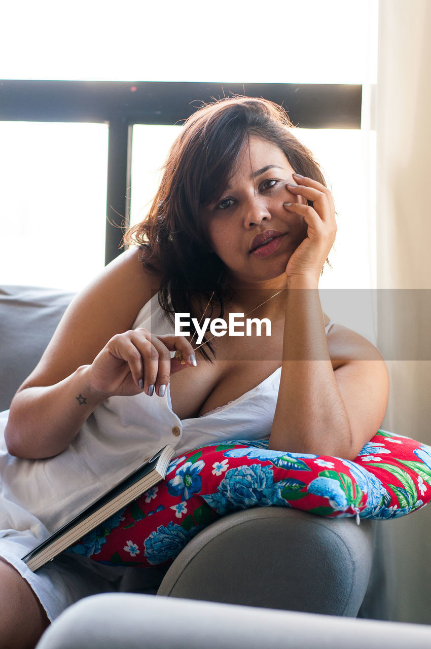 PORTRAIT OF A WOMAN SITTING AT HOME