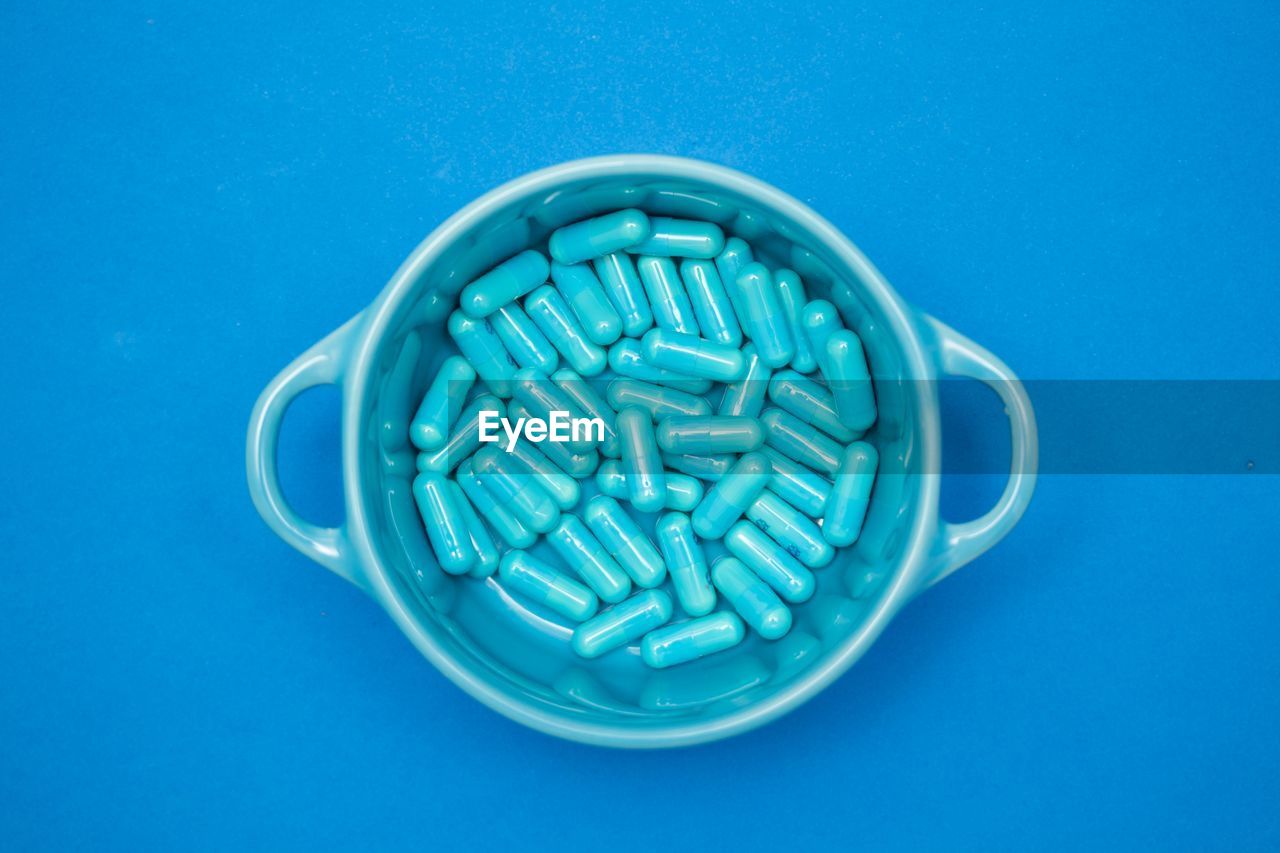 Directly above shot of pills in container blue background