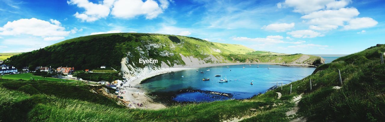 Panoramic view of lulworth cove by mountains against sky