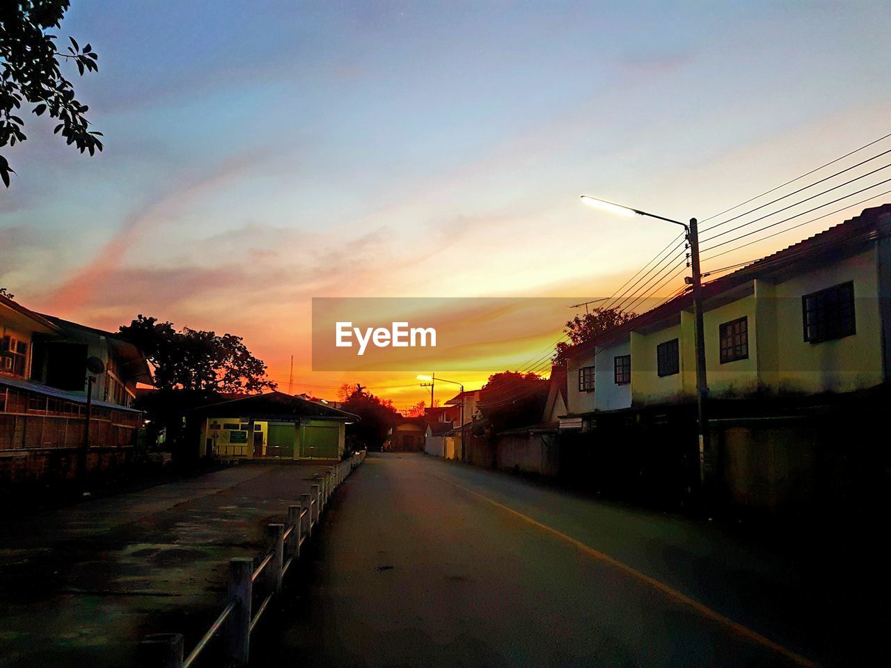 ROAD BY BUILDINGS AGAINST SKY DURING SUNSET