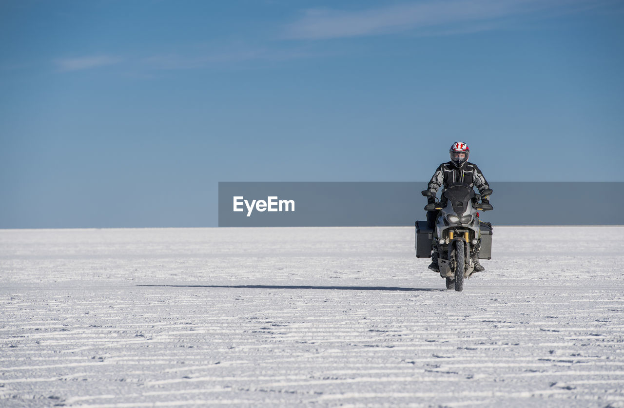 Man riding his touring motorbike on the salt flats of uyuni in bolivia