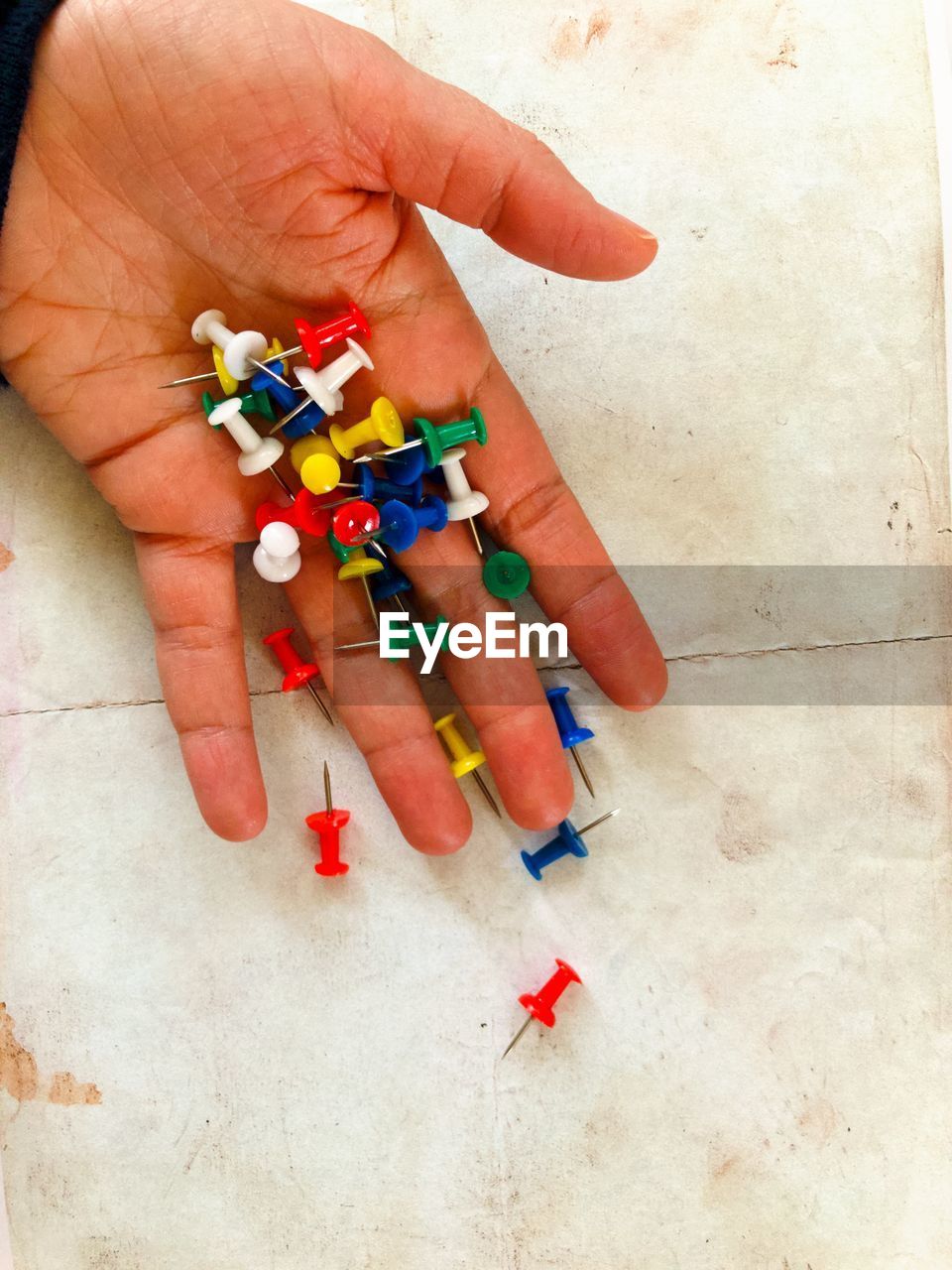 HIGH ANGLE VIEW OF HAND HOLDING MULTI COLORED PAPER