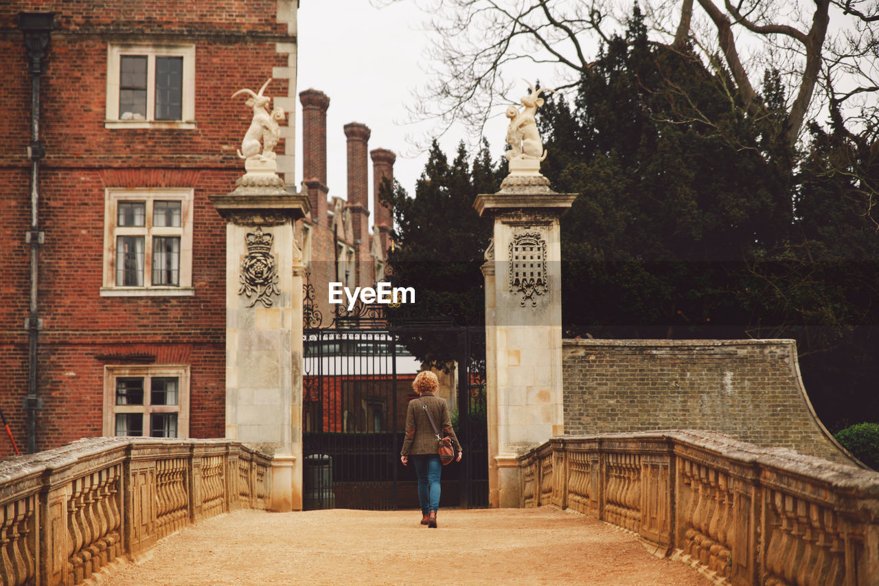 Rear view of woman walking towards building gate