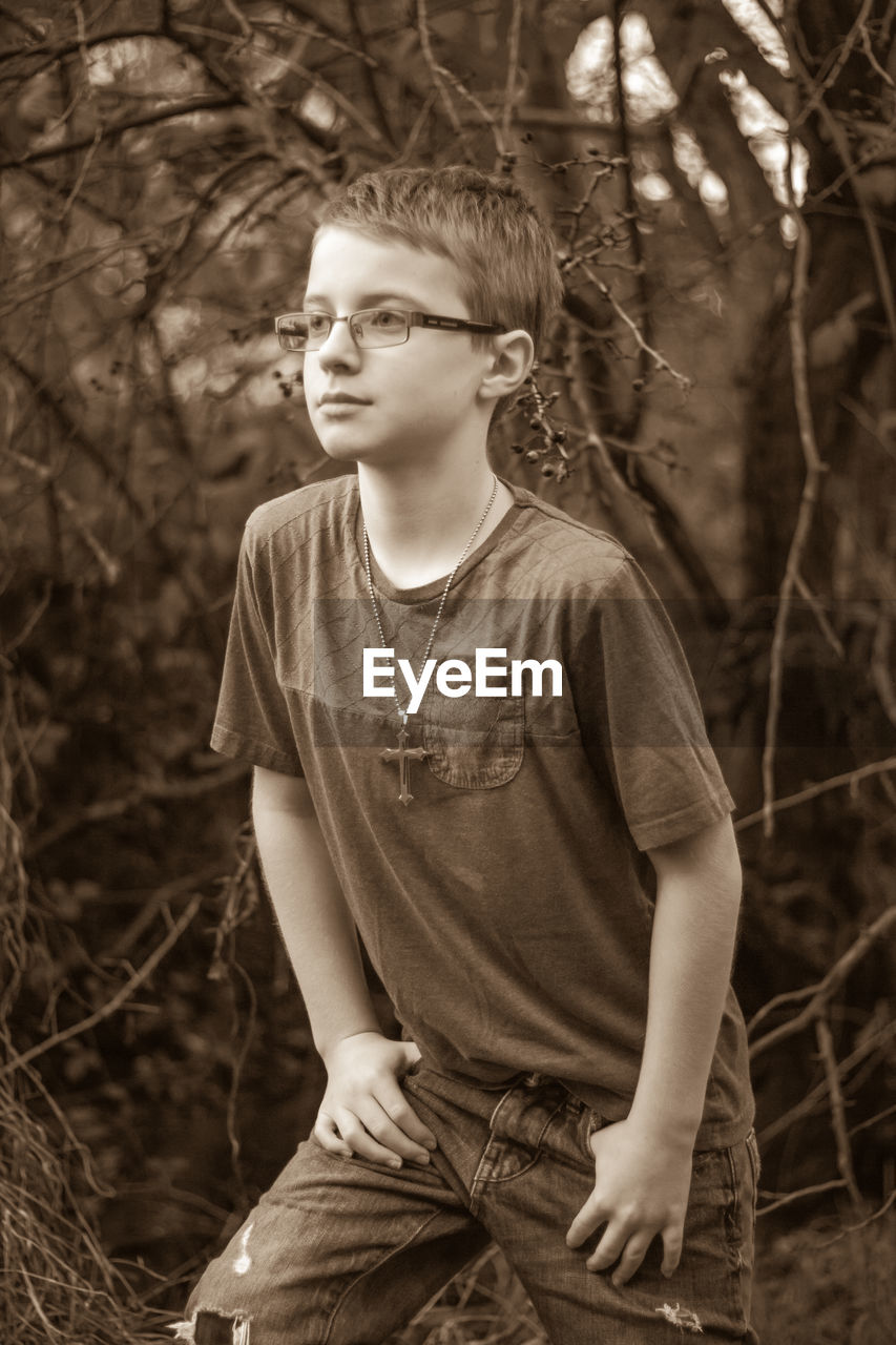 Boy posing against dried plants in forest