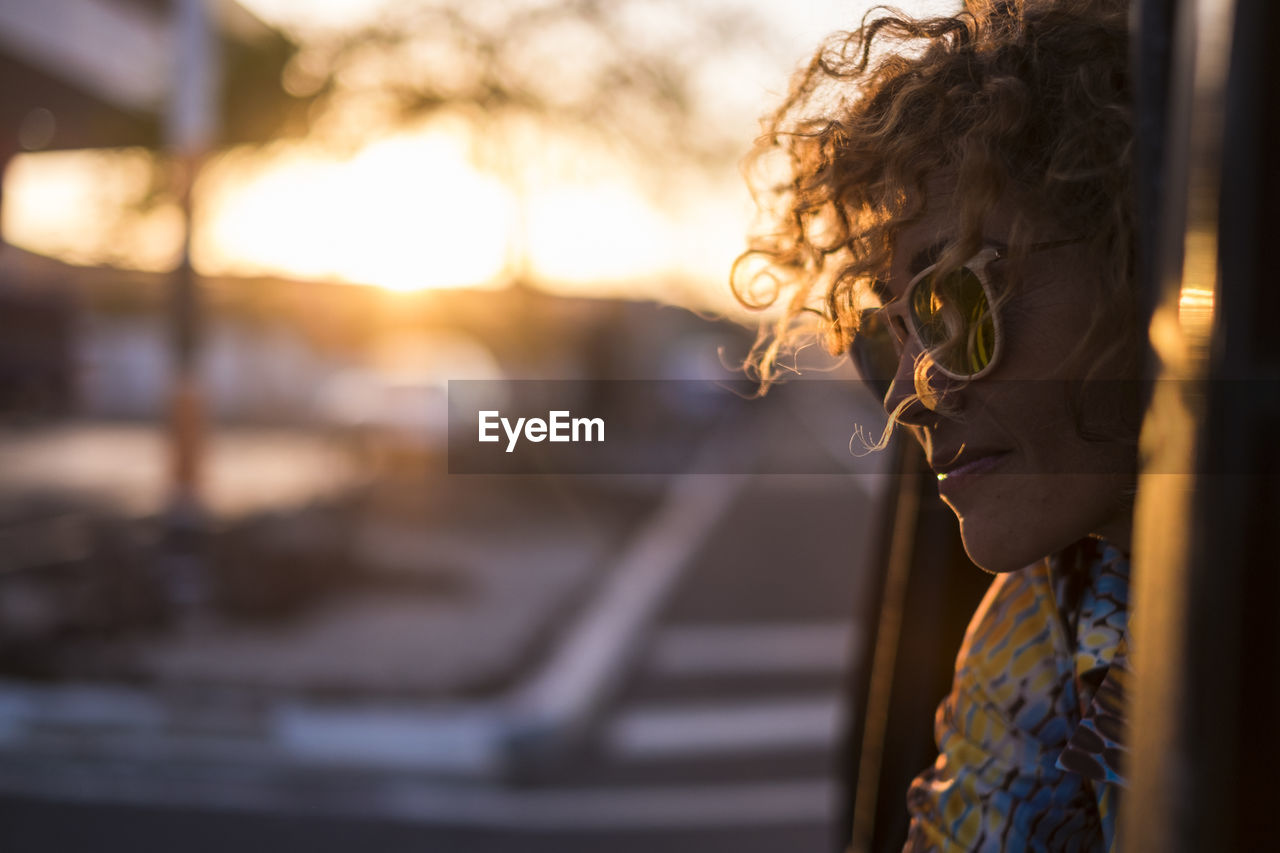 Close-up of woman wearing sunglasses looking away during sunset