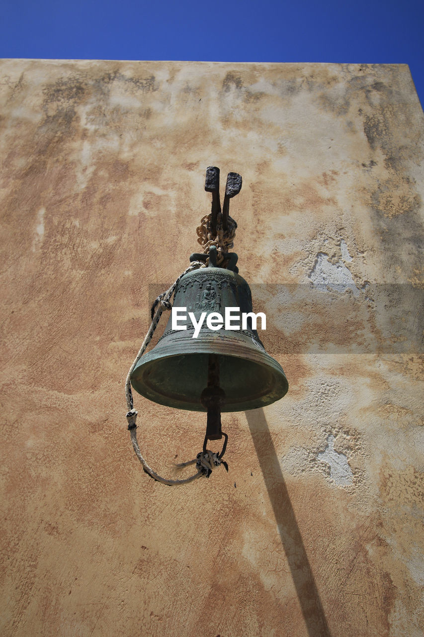 An old bell hanging on the wall of an orthodox church on the island of spinalonga.