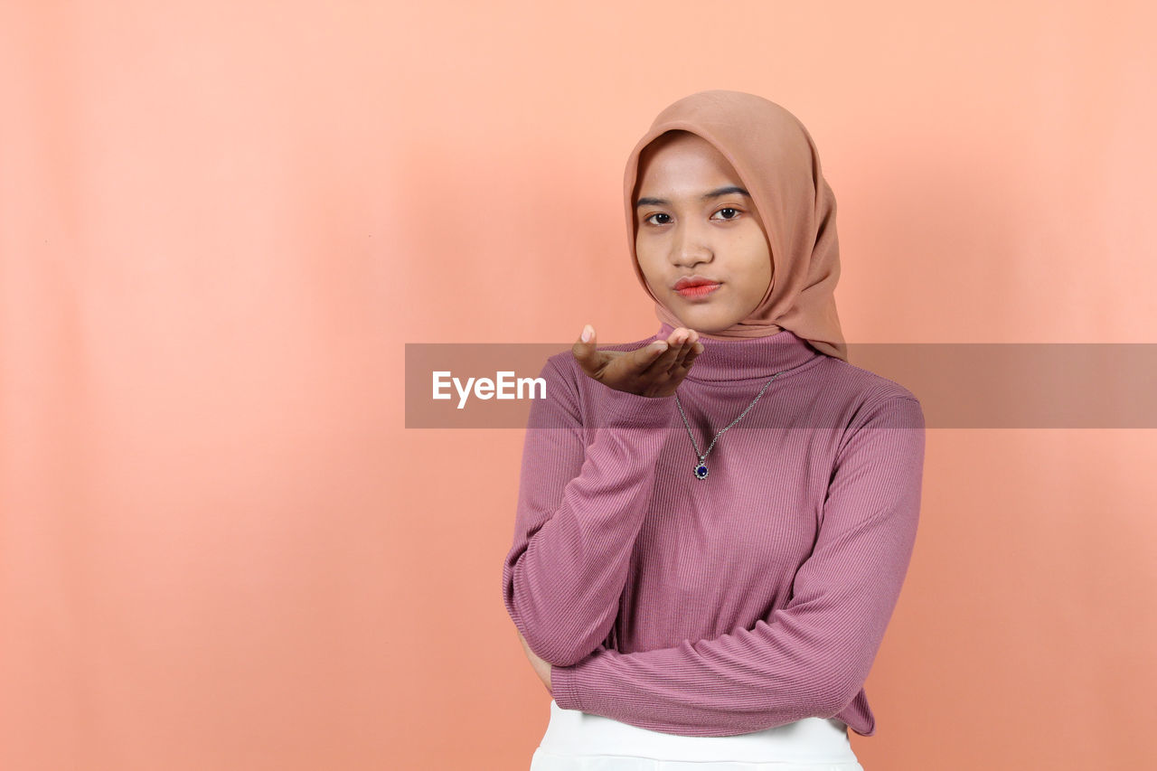 pink, one person, portrait, studio shot, adult, young adult, colored background, hood, women, indoors, looking at camera, sleeve, clothing, standing, waist up, copy space, outerwear, fashion, front view, photo shoot, hairstyle, collar, looking, lifestyles, three quarter length, casual clothing, female, individuality, emotion, serious