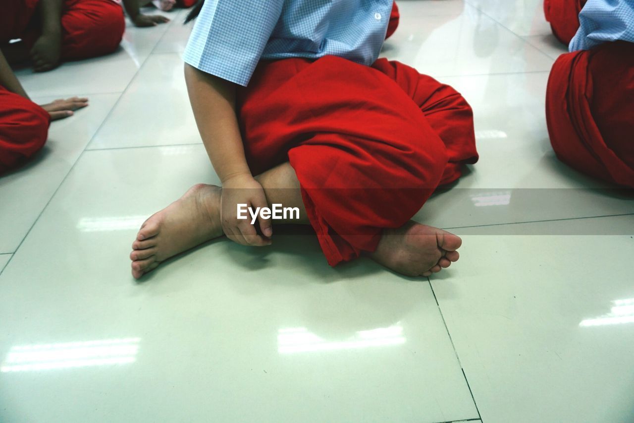 Low section of girl in uniform sitting on floor at home